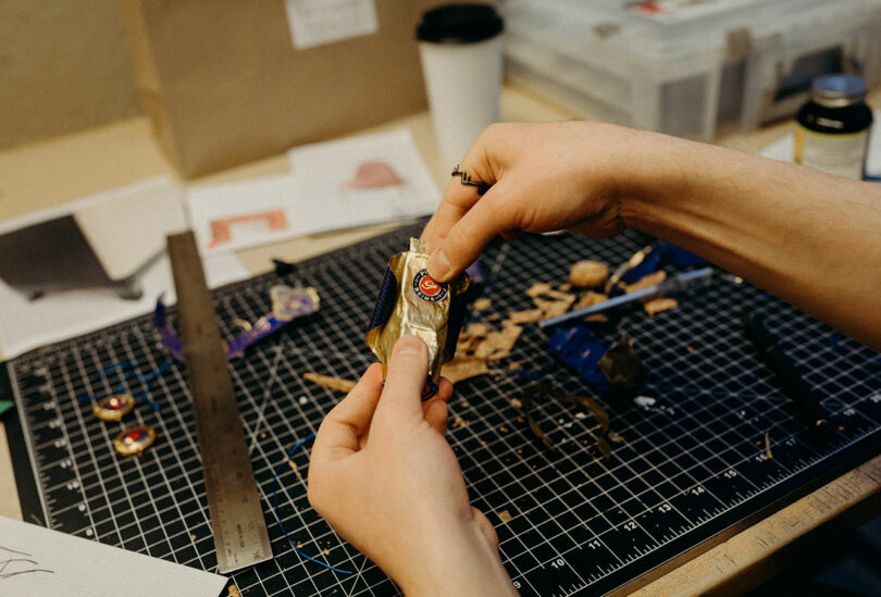 Hands assembling a model from bottle packaging.