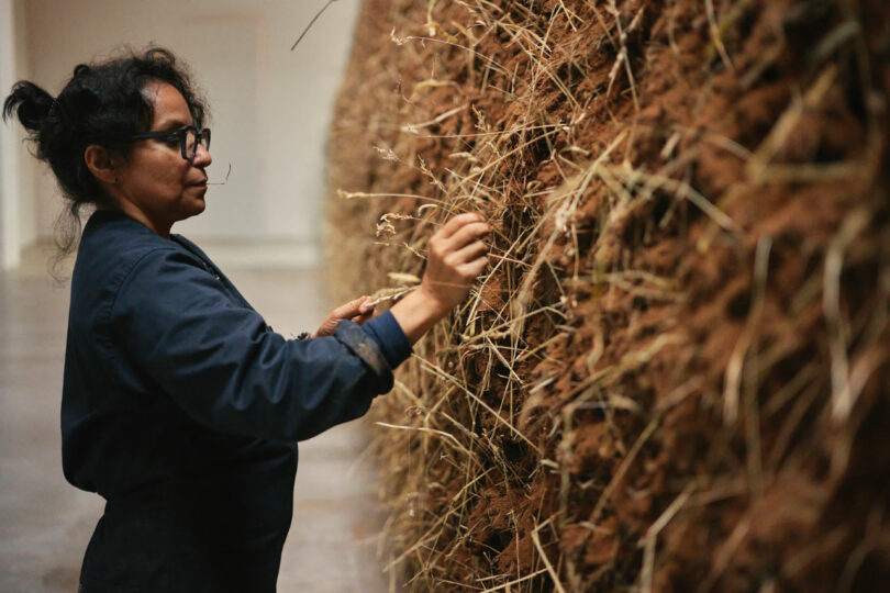 Artist Delcy Morelos places an individual blade of hay