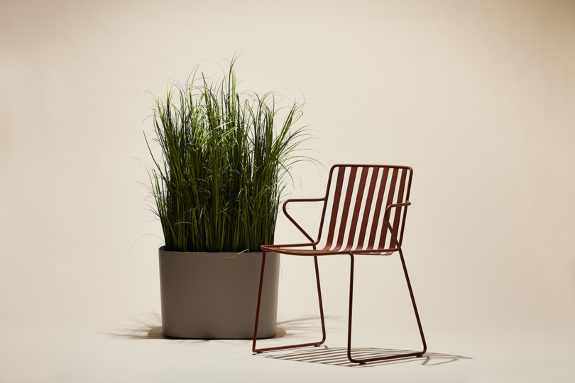 slatted metal outdoor chair next to a large planted bush