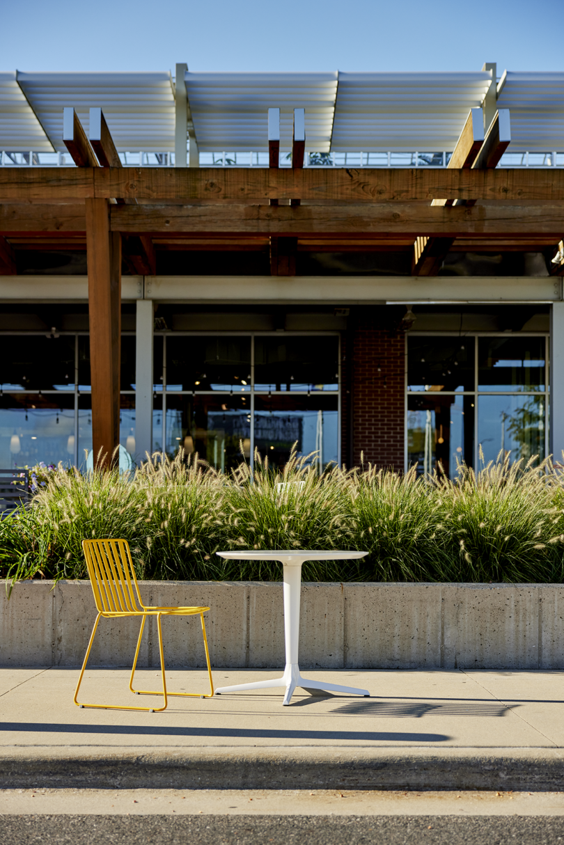 yellow slatted metal outdoor chair at a white cafe table