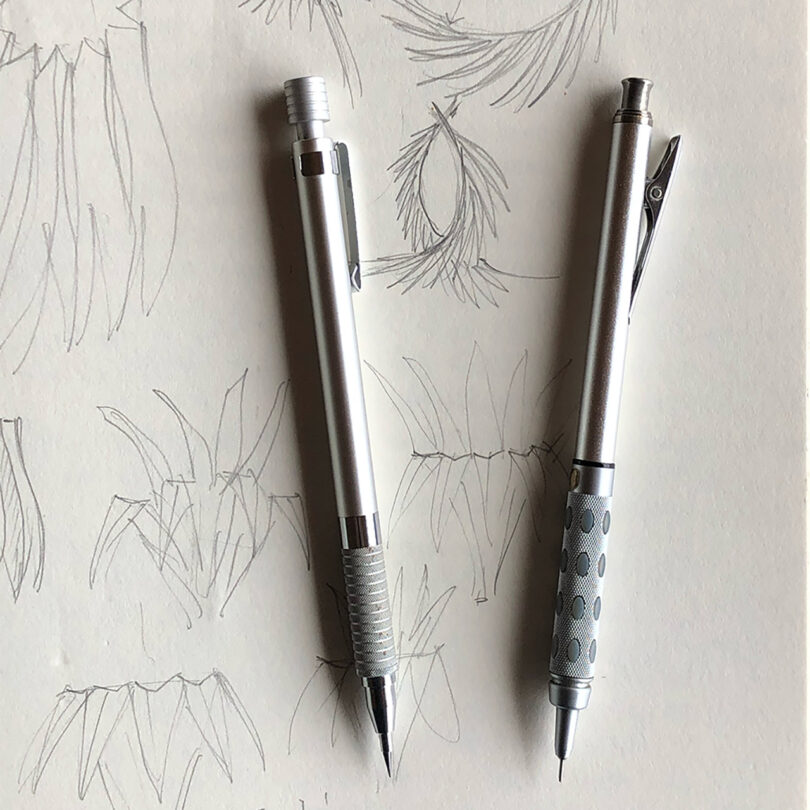 two mechanical pencils laying connected apical of a sketch