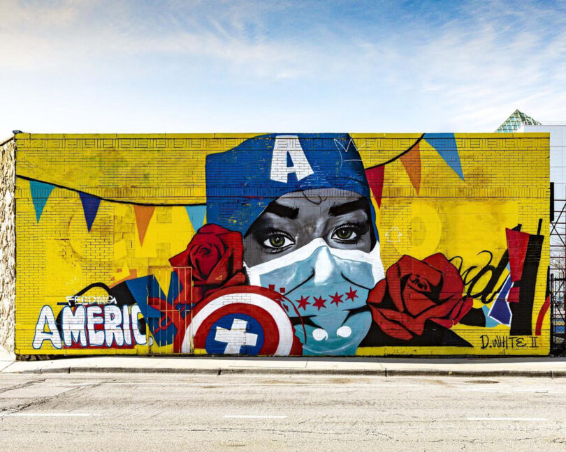large outdoor mural of a woman's face wearing a medical mask and a scrub hat