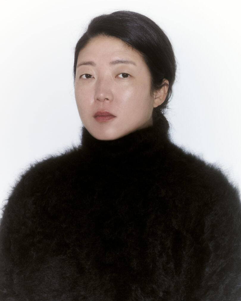 light-skinned woman with black hair pulled back wearing a fuzzy black turtleneck sweater
