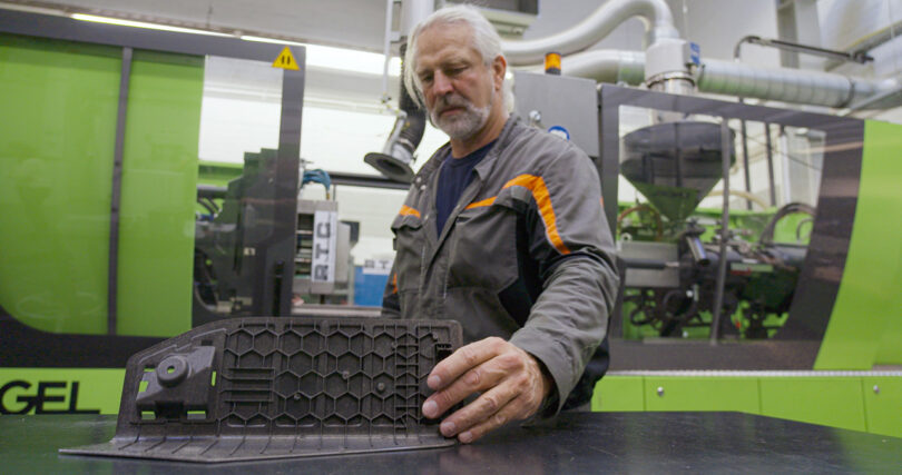 Man at Ford's Cologne, Germany testing facility inspecting footrest made from olive fiber biocomposite 