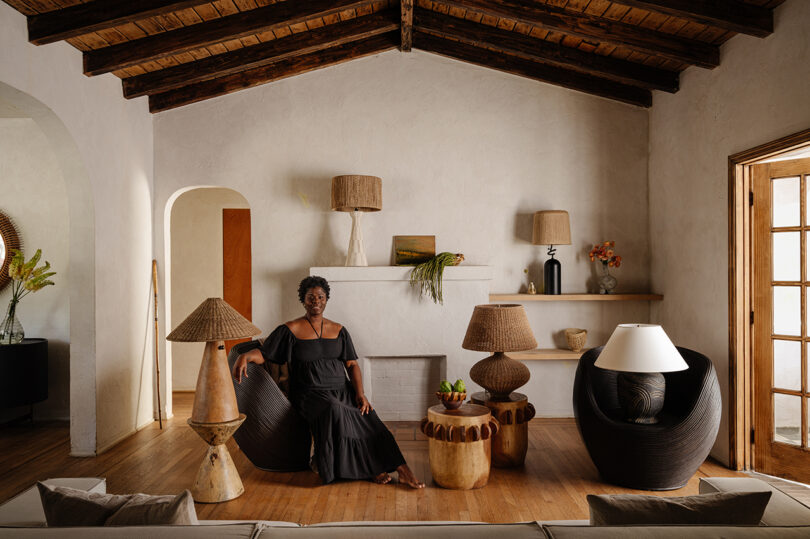 styled room full of lamps, a brown-skinned woman sits on the sofa wearing a long black dress