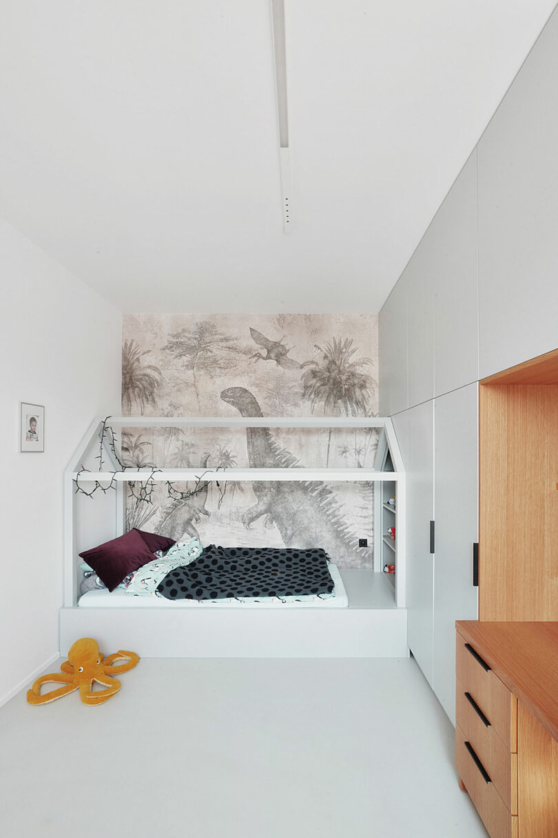 view of modern kids room with house shaped bed frame and wallpapered wall at back