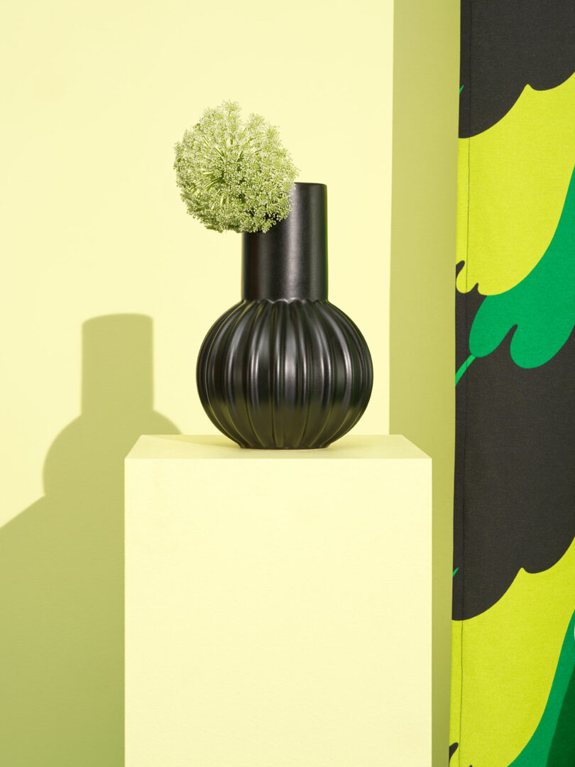black bulbous vase sitting on yellow pedestal