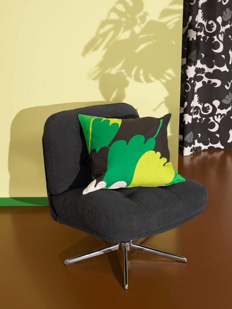 angled view of modern black tufted chair with bold graphic yellow green, and black pillow