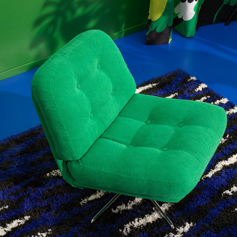 down view of upholstered green tufted chair on blue, black, and white shag carpet