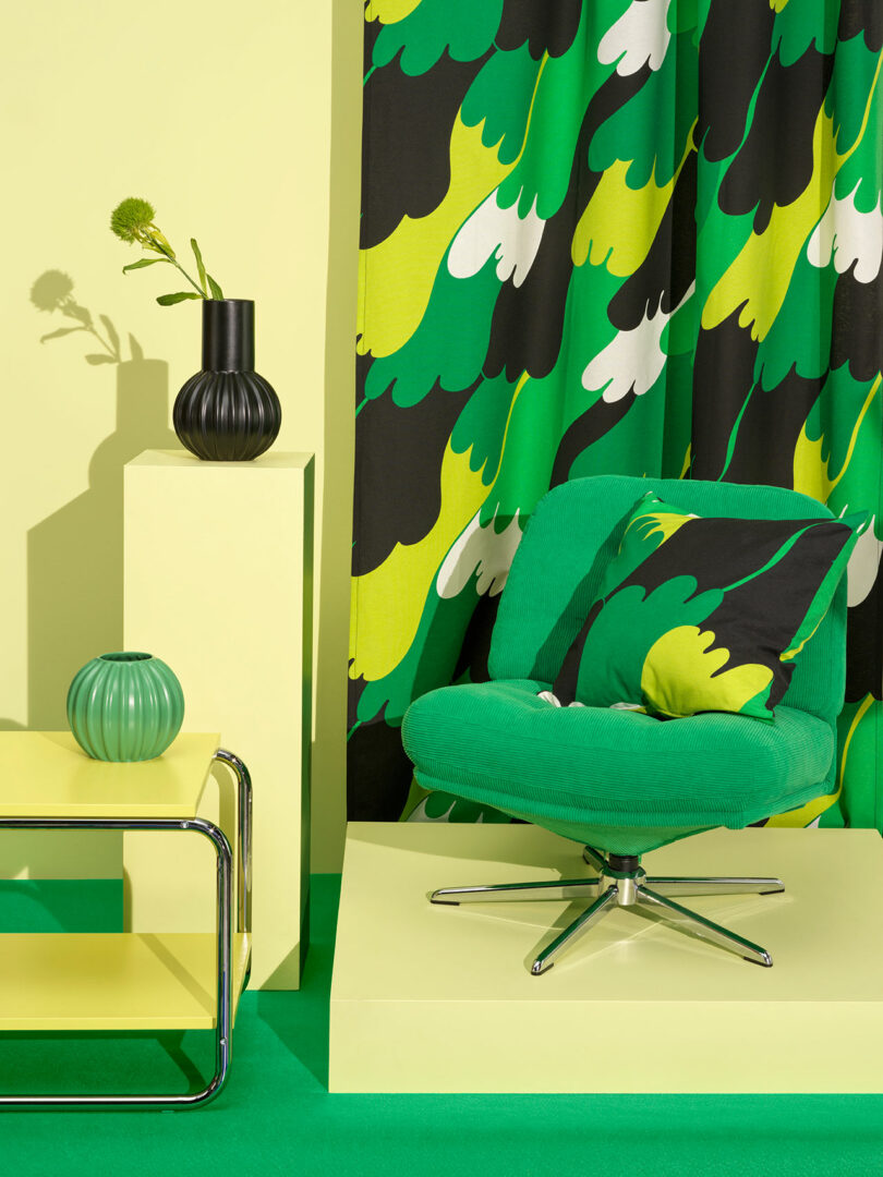 vignette of bright green upholstered tufted chair with bold patterned textiles in yellow, green, black, and white.