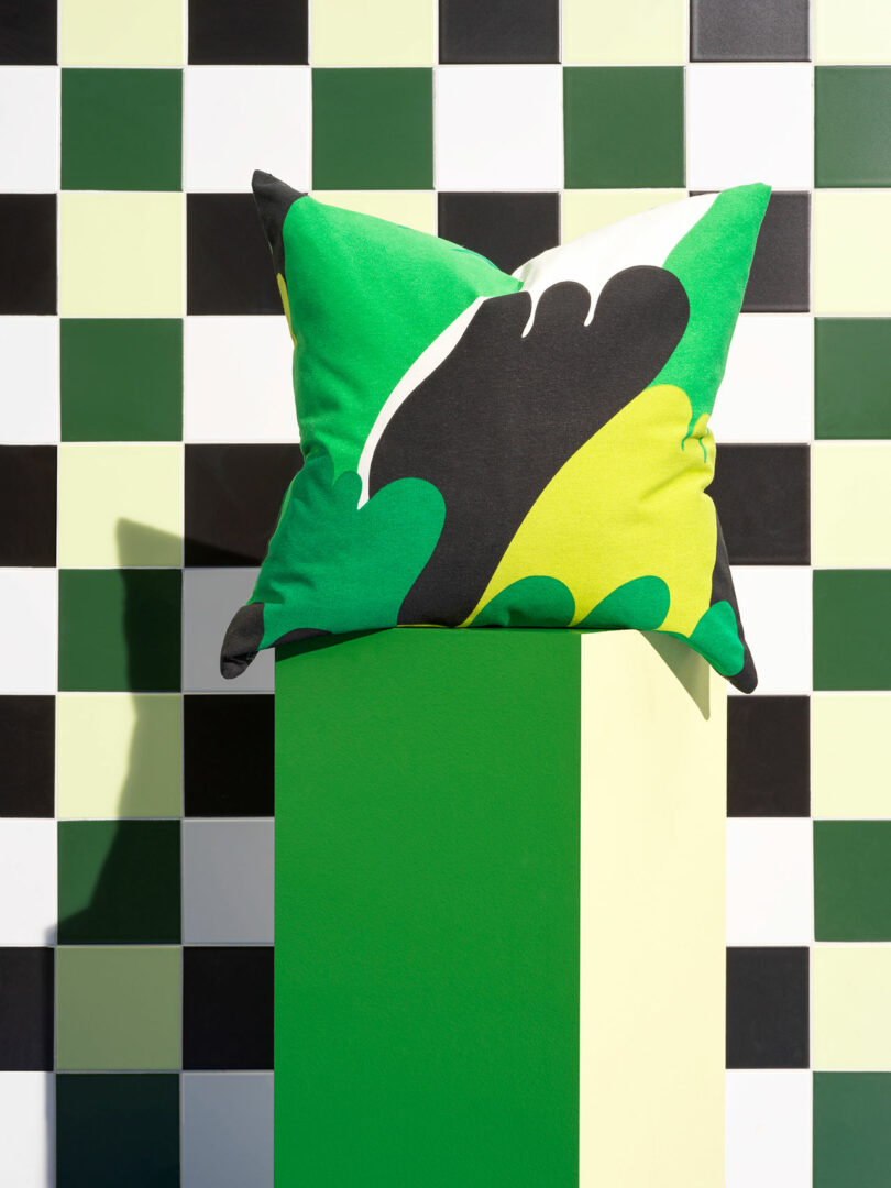 graphic green, yellow, and black pillow in front of checkerboard wall