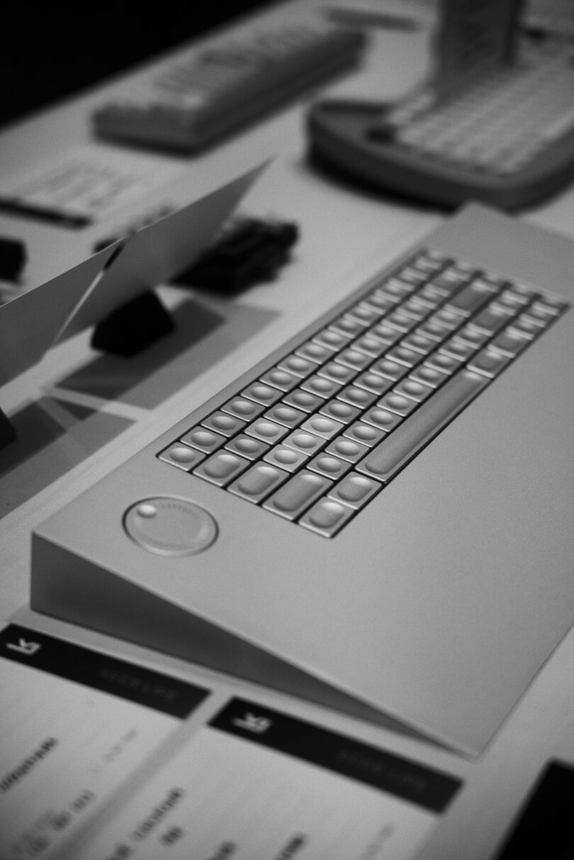Overhead angled black and white photo of all-aluminum The IceBreaker keyboard set across desk beside other mechanical keyboards.