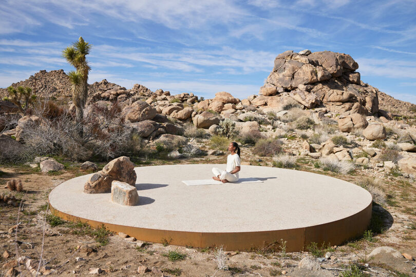 outside shot in desert with large circular concrete patio with person sitting in center meditating