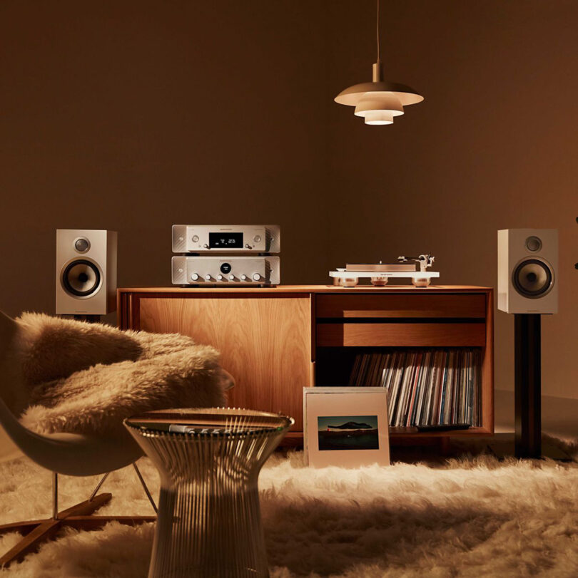 Staged living room with sheepskin rug and sheepskin covered armchair in front of Marantz and Bowers & Wilkins audio turntable system, with records displayed in cabinet underneath.