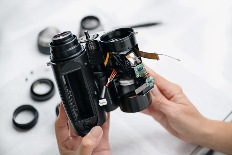 Interior of the SWAROVSKI OPTIK AX Visio smart binoculars exposed, held by a person in two hands.