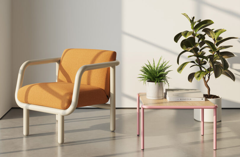 Percy lounge chair in orange upholstery and cream tube frame with small side table and houseplants nearby.