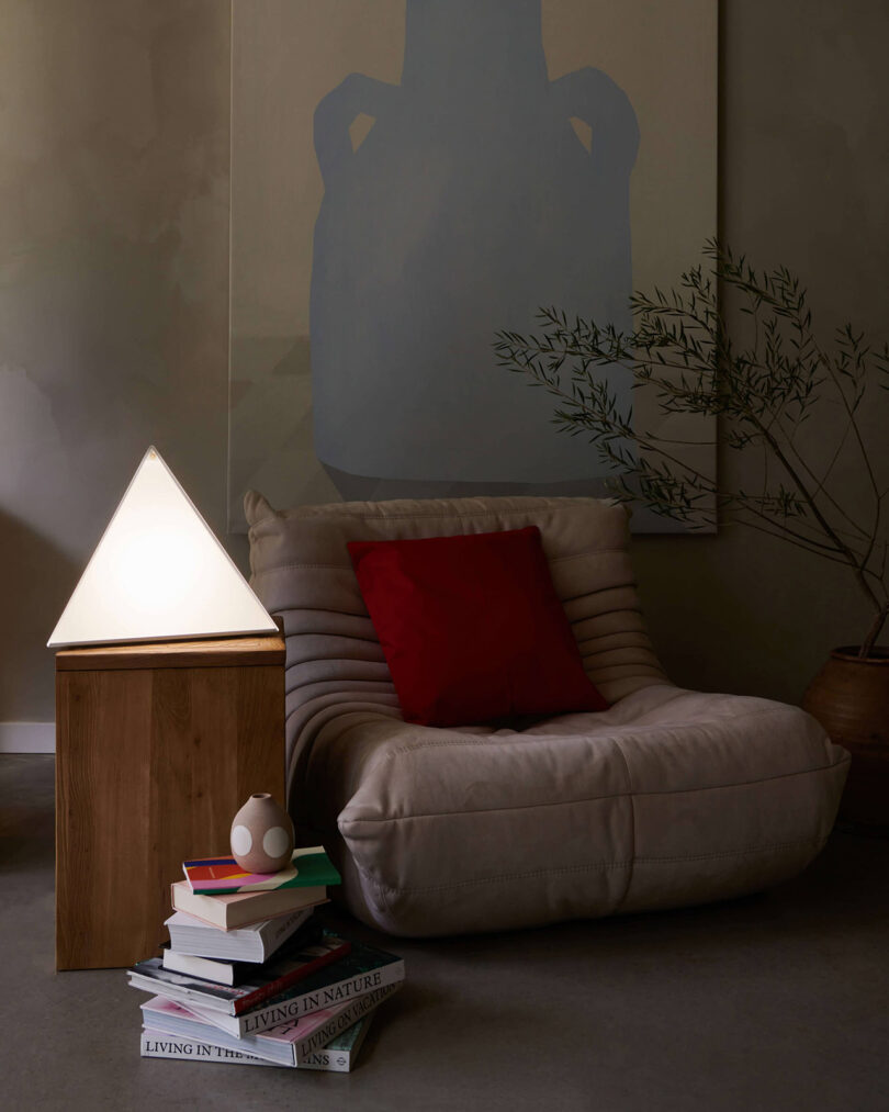 Northern Lights LUXOR seasonal affective disorder pyramid shaped lamp set on a side pedestal table next to TOGO side chair and a stack of books.