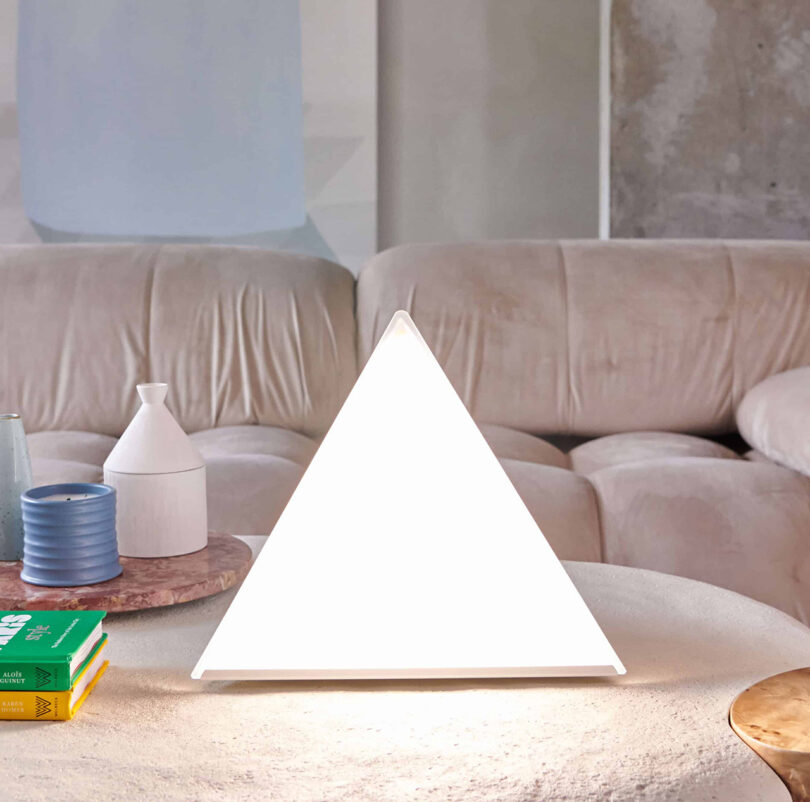 Northern Lights LUXOR seasonal affective disorder pyramid shaped lamp set on a living room coffee table near decorative ceramics and candle.