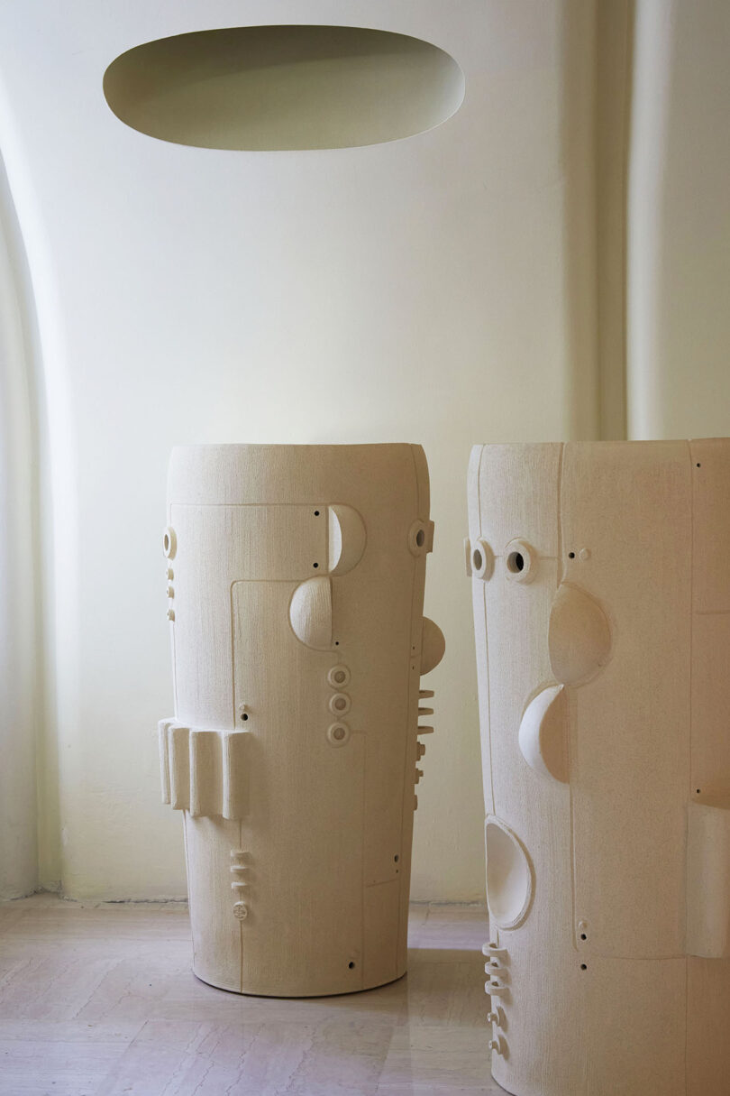 two tall white ceramic pieces with geometric shapes added to their surfaces
