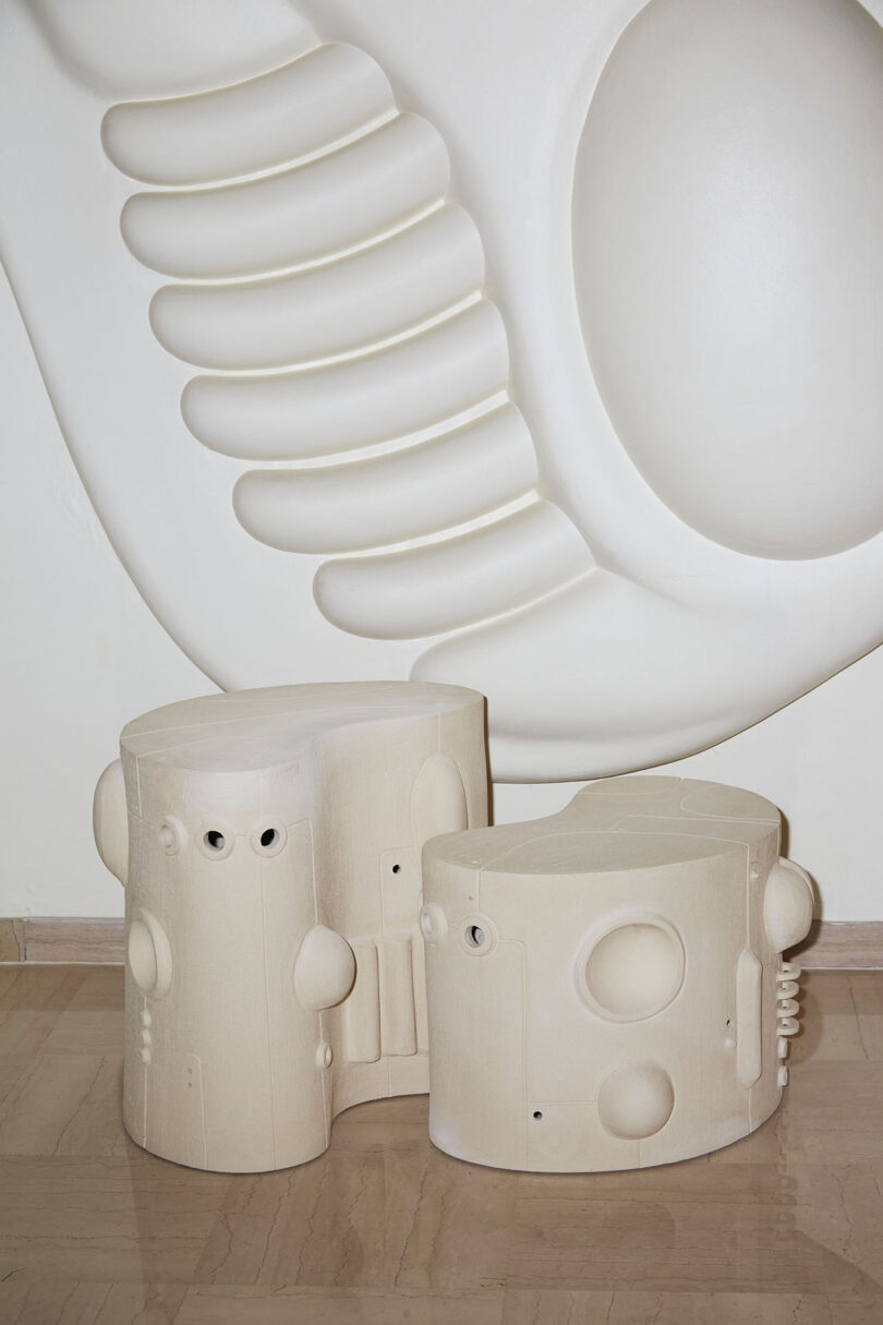 two white ceramic pieces with geometric shapes added to their surfaces