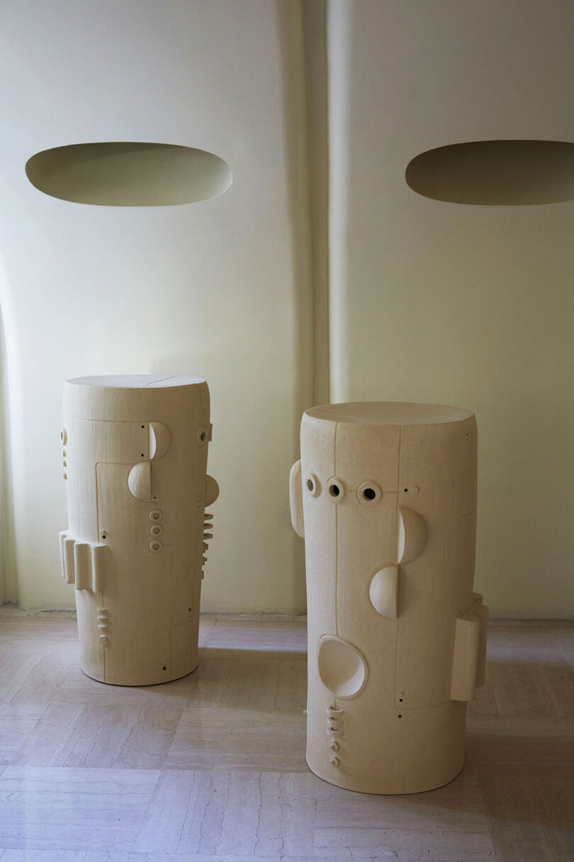 two tall white ceramic pieces with geometric shapes added to their surfaces
