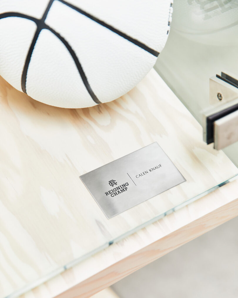 Small metal placard stamped with Reigning Champ and Valentine Knauf's name, with white basketball just overhead.