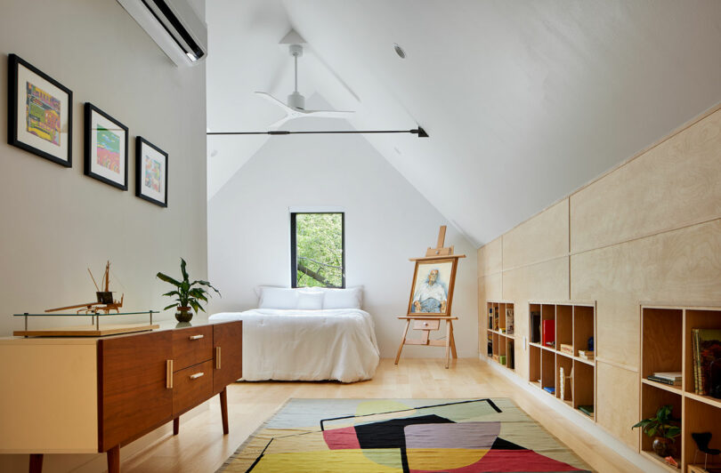 A bedroom with bed, easel, and dresser.