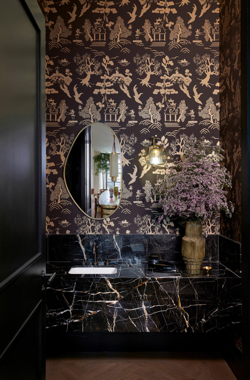 dark and moody bathroom with patterned wallpaper and dark grainy sink