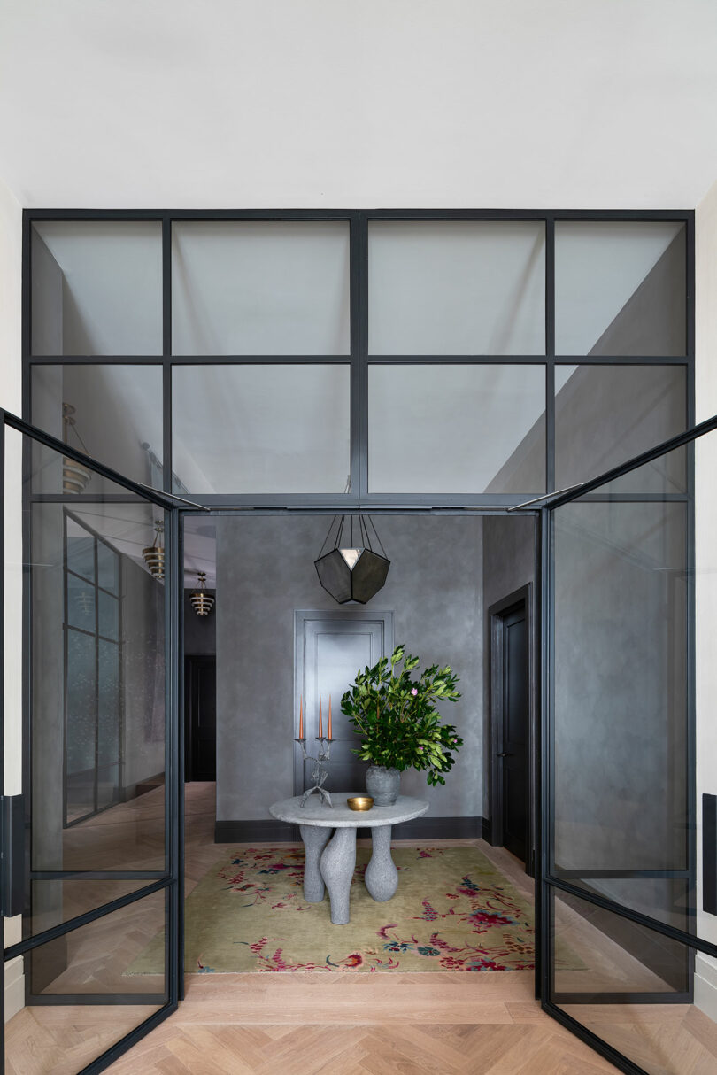 interior view into foyer of modern apartment with dark gray walls and glass wall of windows as a divider