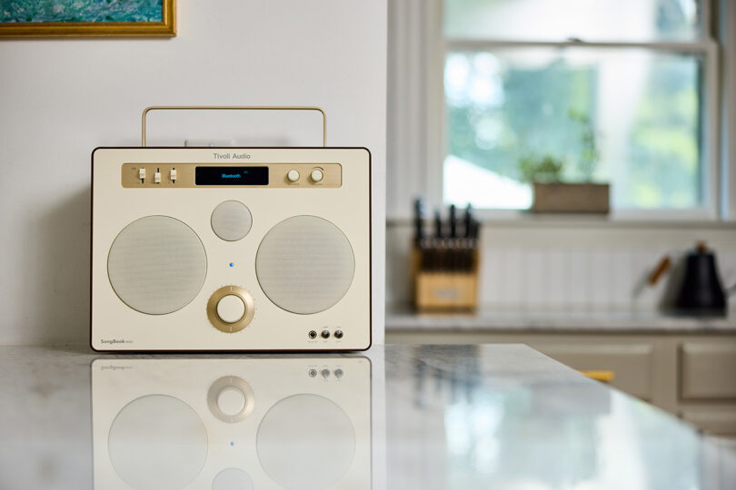 Tivoli Audio SongBook MAX wireless speaker radio in cream and brown finish set on a marble kitchen countertop