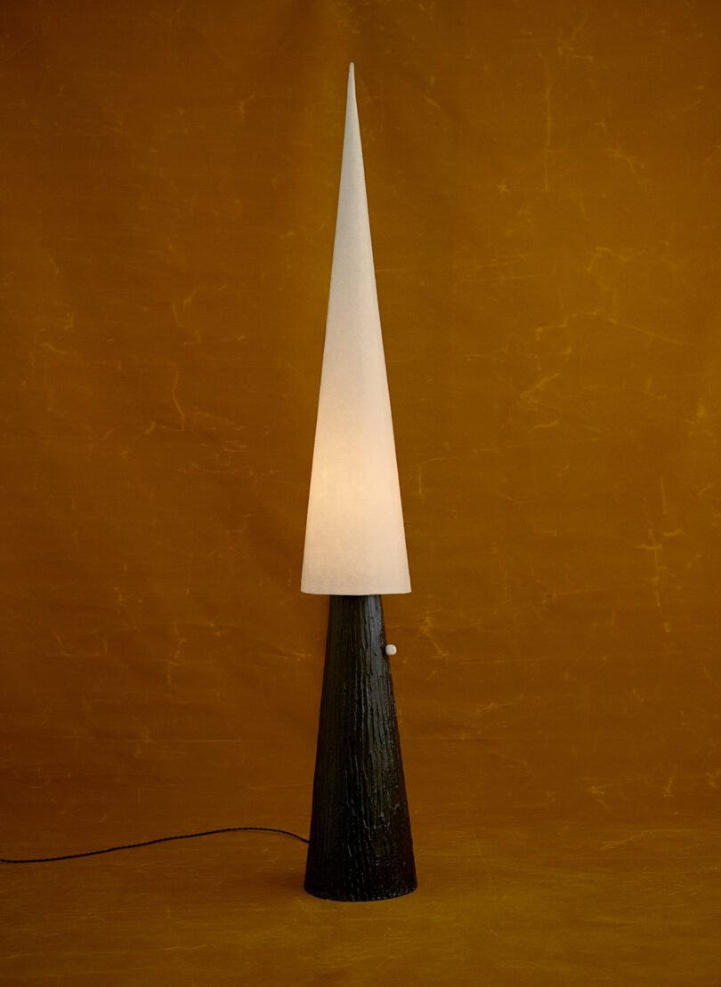 floor lamp with dark, slim base and tall, popinted shade