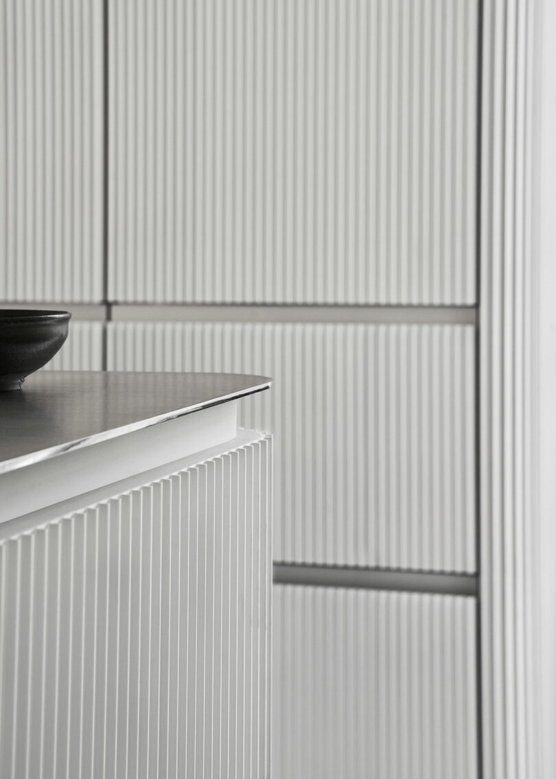 closeup edge view of modern kitchen with aluminum freestanding island and bank of cabinets with extruded door profiles