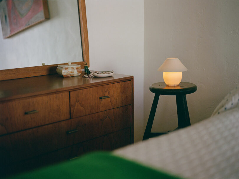 A tiny orb-shaped lamp with traditional shade sitting on a stool.