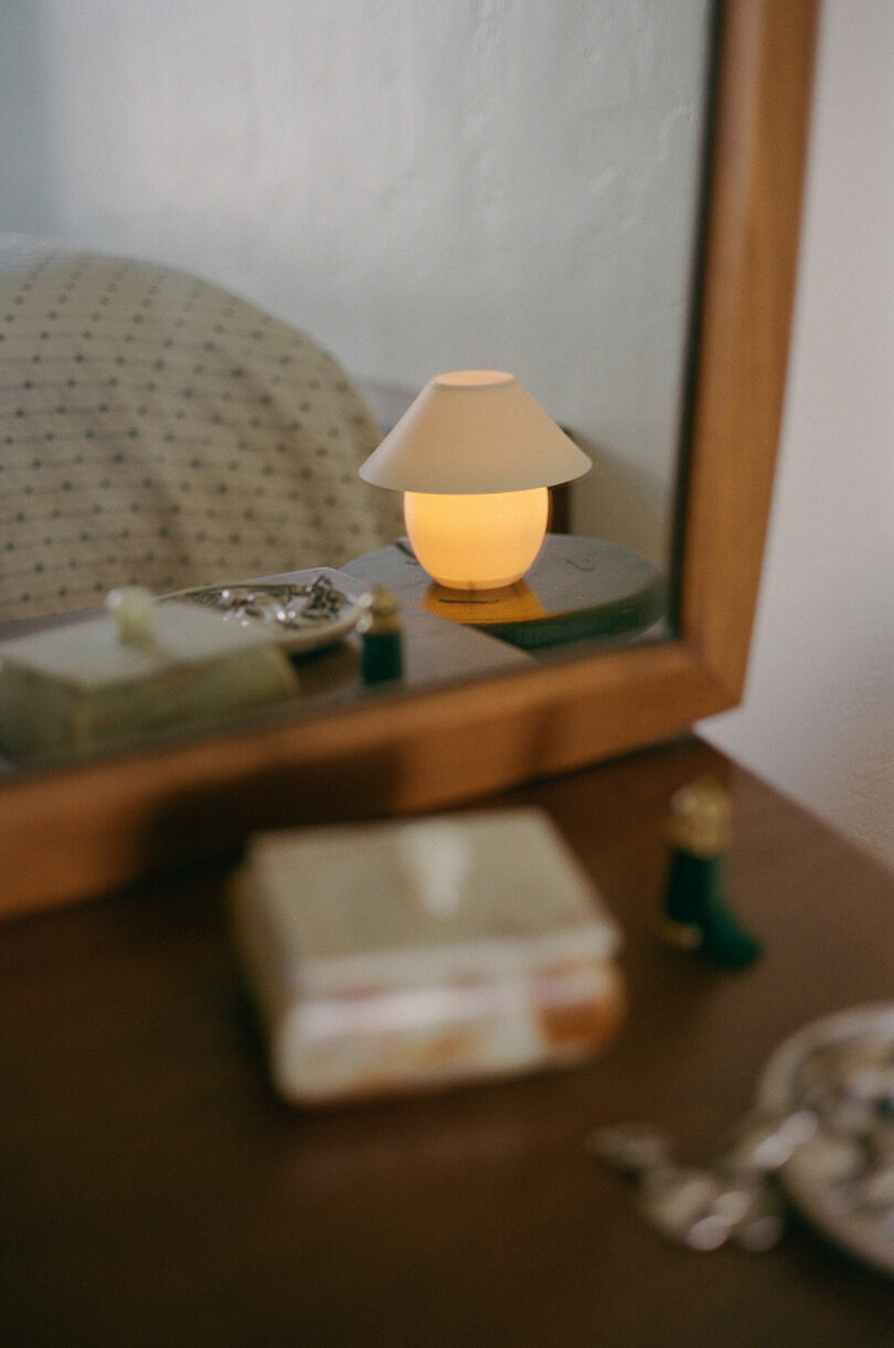 A mini orb-shaped lamp pinch accepted shadiness sitting connected a stool successful nan reflection of a mirror.