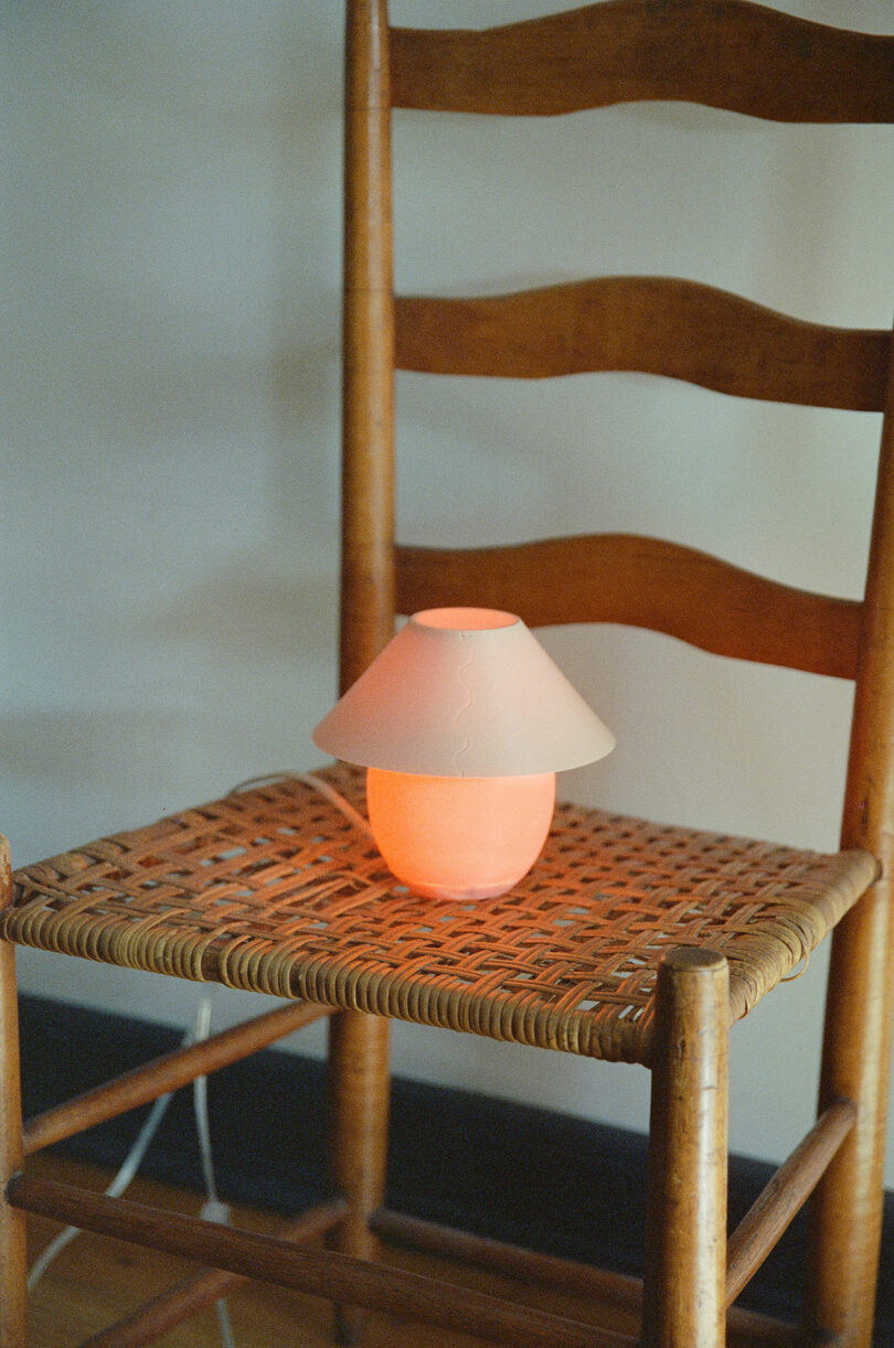 A tiny orb-shaped lamp with traditional shade sitting on a chair.