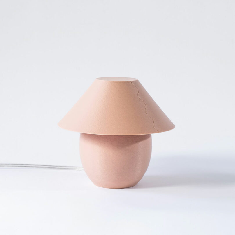 A tiny, blush colored orb-shaped lamp with traditional shade turned off.
