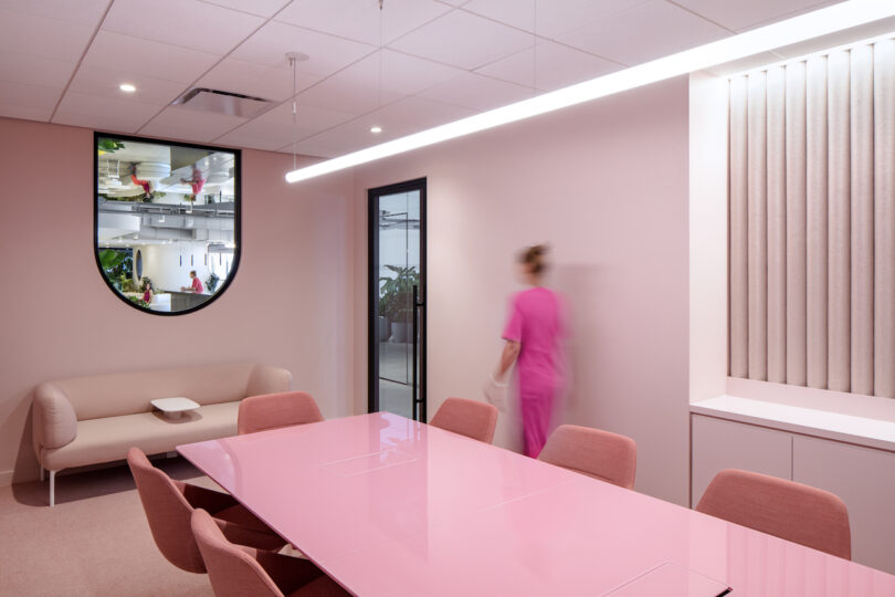 woman walking across pink conference room