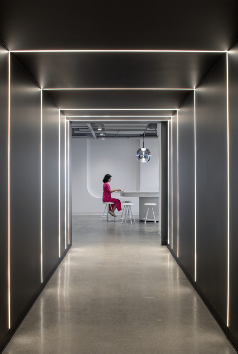 woman sitting at a table next to long hallway