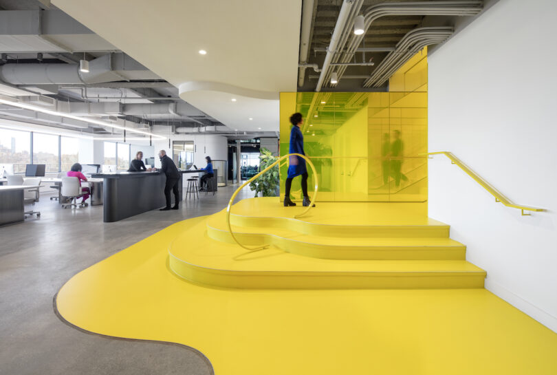 person walking up yellow steps in an office
