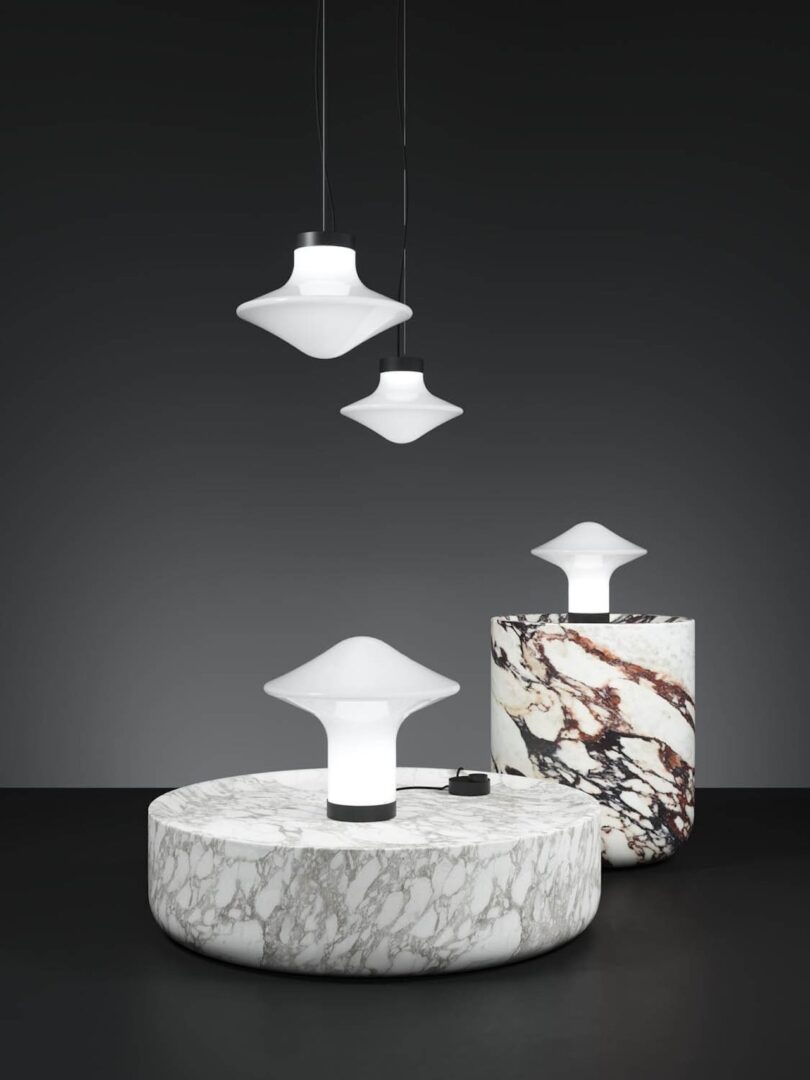 a pair of spinning top pendant lights hanging above and two table lamps on marble tables