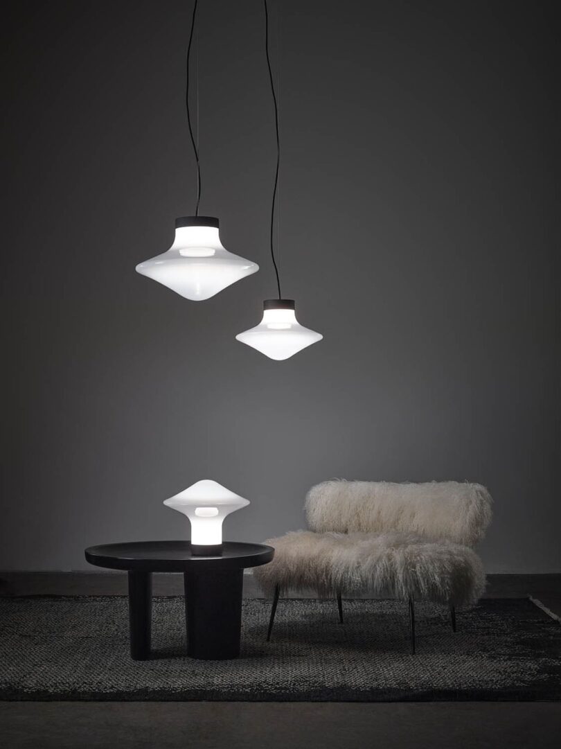 a pair of spinning top pendant lights hanging above and a table light on a side table next to a white sofa