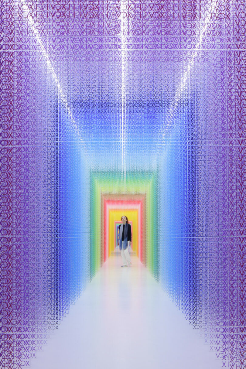 woman walking through a colorful installation of acrylic transparent sheets