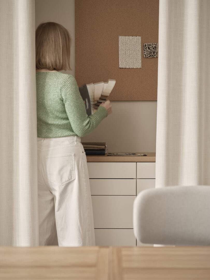 woman next to white drawers behind curtains