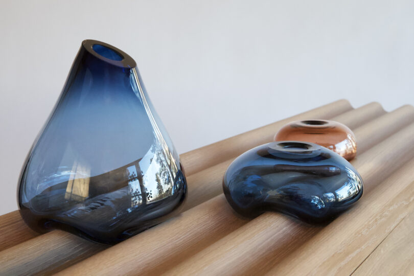 wood console surface with three glass vases on it