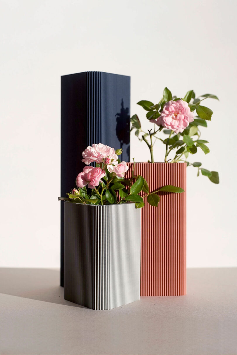 three triangle vases with flowers in them