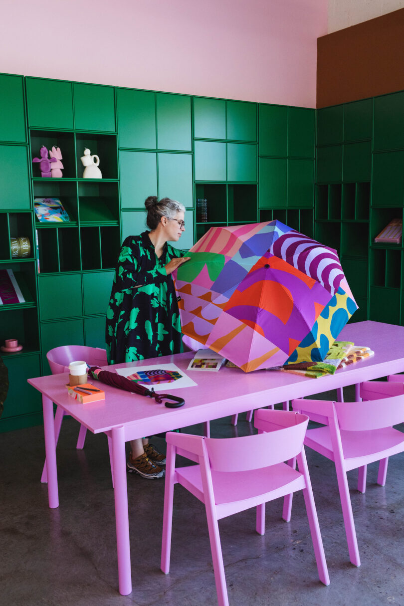 woman holding colorful abstract umbrella in her studio