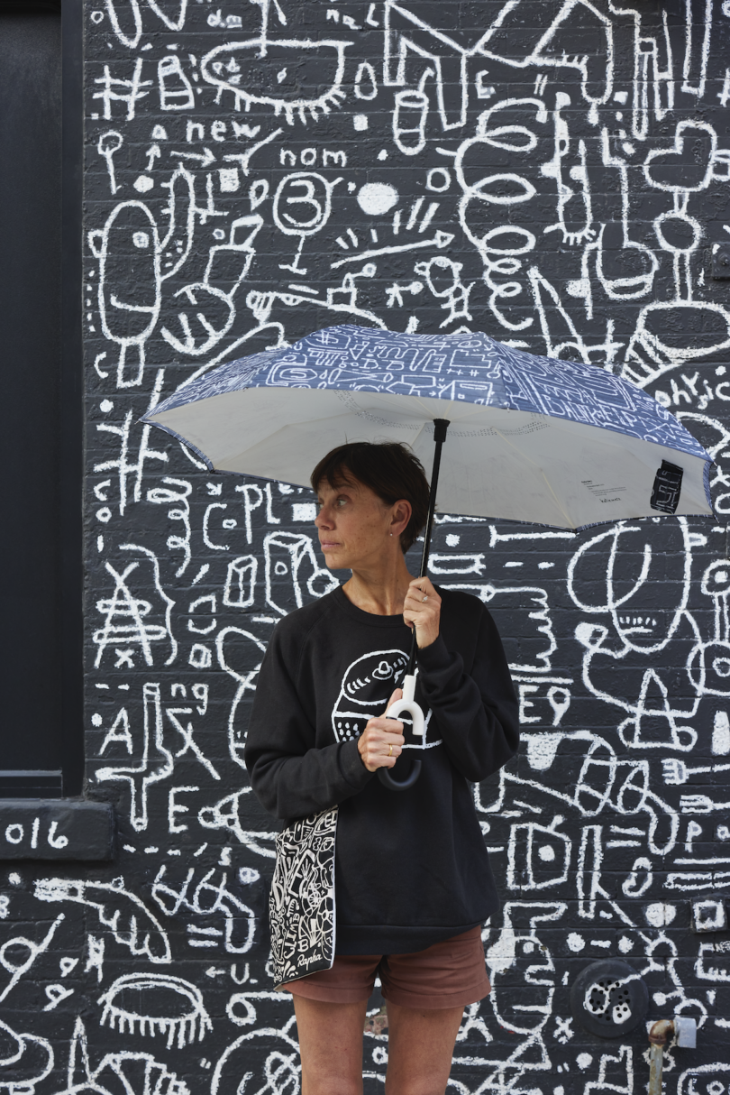 woman holding graphic umbrella in front of graphic wall mural