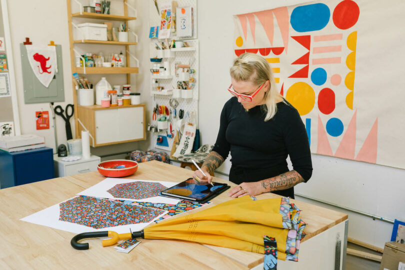 woman drafting connected an ipad adjacent to a yellowish umbrella successful her creator studio