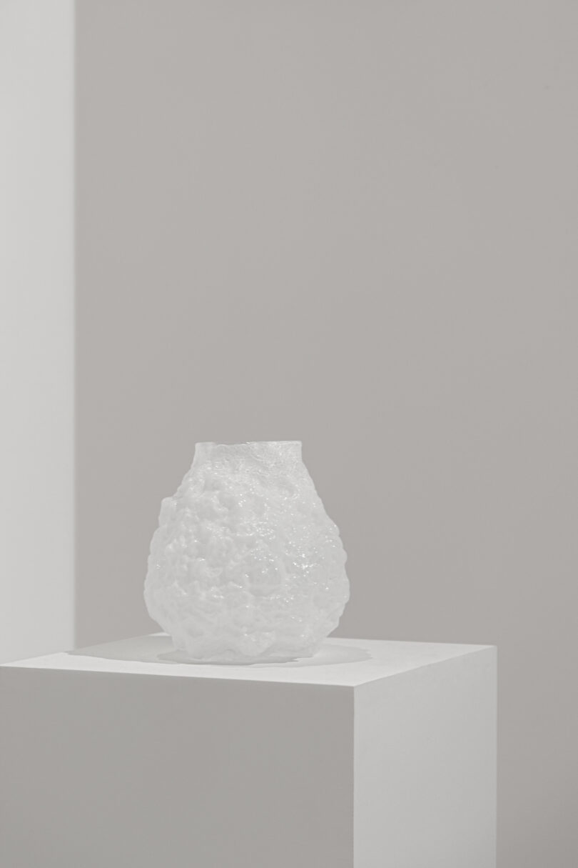 A white vase sits on a white pedestal in Villa Albertine.
