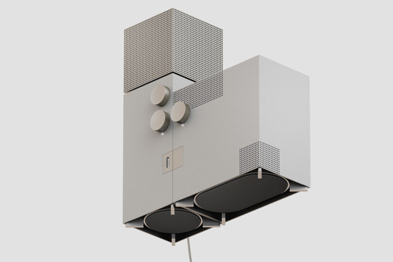 Two piece audio speaker system shaped after brutalist church, with three knob controls and perforated speaker cube on top. Entire speaker system is floating in the air with a cord visible below.